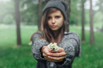 Młoda kobieta trzyma białe kwiatki w parku.
