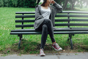 Młoda kobieta siedzi na ławce w parku.