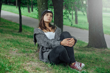 Młoda kobieta myśli pod drzewem w parku.