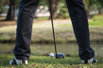 Close up of golf ball on a tee with the driver positioned ready to hit the ball.