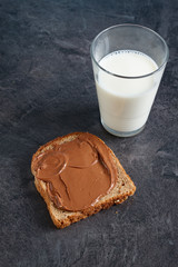 Slice of bread with chocolate cream and a glass of milk