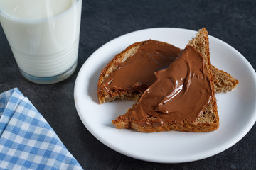 Slice of bread with chocolate cream and a glass of milk