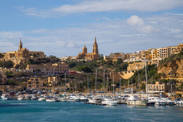 Fototapeta premium Bay view of Mgarr, town and harbour where ferries dock at the east end of island Gozo, Malta. Popular touristic route, attraction and destination.