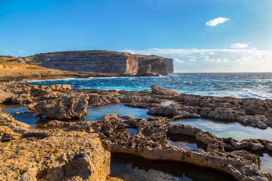 Fototapeta Malta, Gozo Island. Beautiful limestone cliffs facing the ocean near Dwejra Bay with water pools and riffs as seen from the Azure Window.