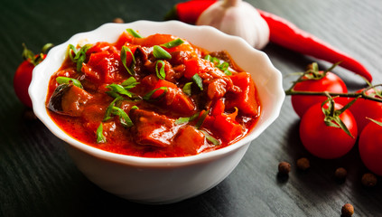 Goulash. Vegetable rague with eggplant, pepper, tomato and carrot in white bowl on dark wooden background