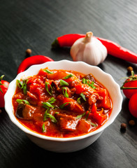 Goulash. Vegetable rague with eggplant, pepper, tomato and carrot in white bowl on dark wooden background
