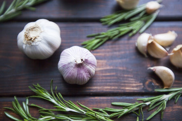 Flavour for any Meal. Garlic bulbs and rosemary branches on a dark wooden table, close up