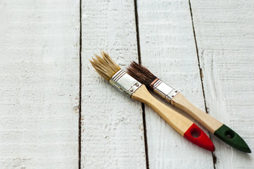 Two brushes - light and dark - on a wooden background.
