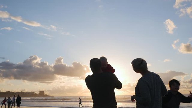 Dolly shot of happy family at beach against sky