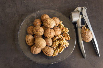 Walnuts lie in a glass dish along with a Nutcracker. Healthy food.