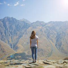 Fototapeta premium Hiker with backpack standing on top of the mountain and enjoying valley view at sunrise