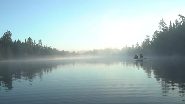 Rear view of people sitting in boat on lake against clear sky