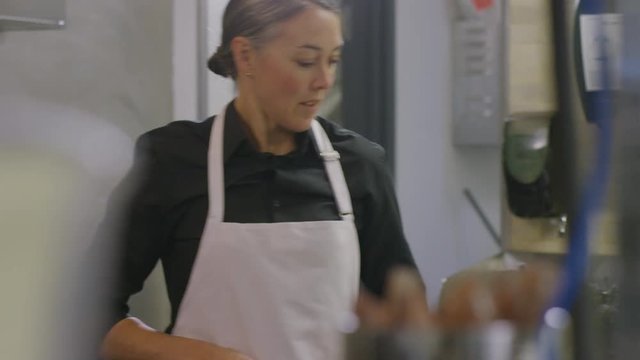 Handheld shot of female chef working at restaurant kitchen