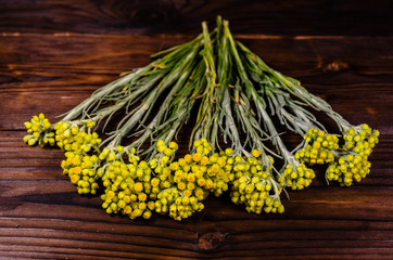 Medicinal plant helichrysum arenarium on wooden table. Top view