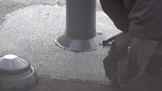 Roofer installing chimney using bitumen and gas flame
