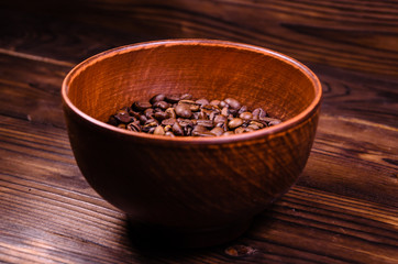 Roasted coffee beans in bowl on wooden table