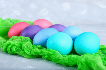 Colored Easter eggs on a green gauze on a gray concrete background.