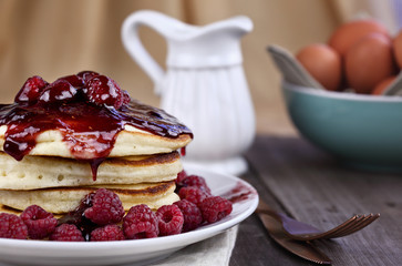 Delicious homemade golden pancakes with fresh raspberries and raspberry syrup. Extreme shallow depth of field.