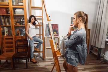 two girls in an artist studio. paints model