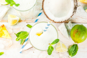 Tropical cocktail, pina colada, pineapple and coconut mojito or smoothies, with lime and mint, on a light blue background copy space
