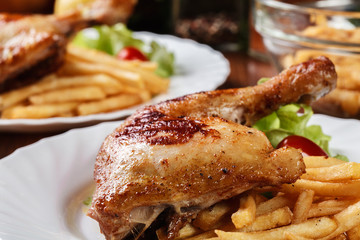 Roasted chicken legs with french fries and lettuce
