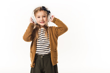 little child listening music with headphones and looking at camera isolated on white