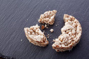 Broken crispbread on stone plate. Dark background. Copyspace for text.