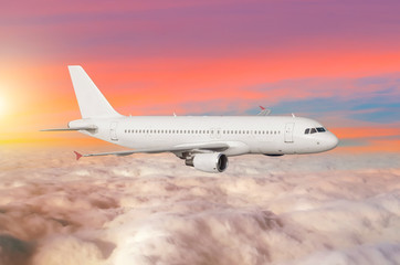 Fototapeta na wymiar Flying airplane above the clouds horizon sky with bright sunset colors.
