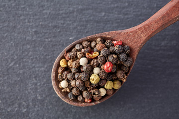Chinese pepper, Sichuan pepper in wooden spoon on black slate stone plate