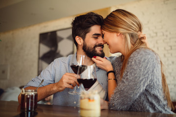 Close-up of a beautiful romantic couple having romantic moments, drinking red wine while celebrating Valentine's Day or anniversary.