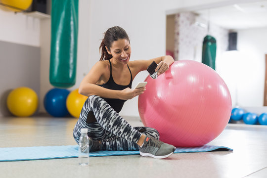 Young woman sitting beside pilates ball in gym