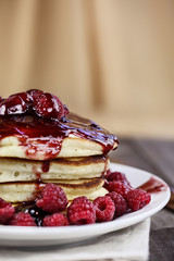 Delicious homemade golden pancakes with fresh raspberries, and raspberry syrup. Extreme shallow depth of field.