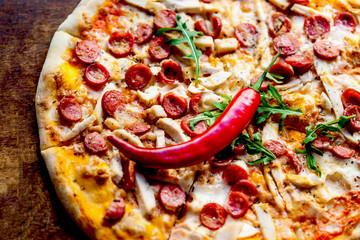  Cheese pepperoni pizza with chilli pepper and  delicious toppings  on a dark wooden background. Top view