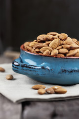 Whole almonds in bowl over a wooden table against a rustic background.
