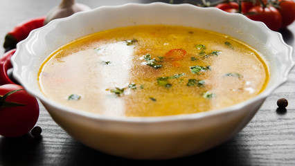 Bowl of chicken soup with noodle and vegetables on a dark wooden background