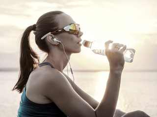 Running woman in sport sunglasses drink. Female runner with her