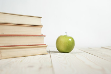 Stack of books and apple on the table