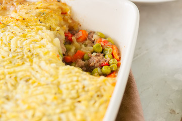 Shepherds pie -  Irish traditional food. Served in a ceramic dish on a white stone background.