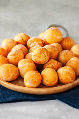 Small cottage cheese doughnuts (castgnole) served on a wooden plate. White stone background.