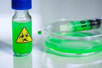 biologically dangerous substance in a syringe, a vial and a petri dish on a table in a chemical laboratory