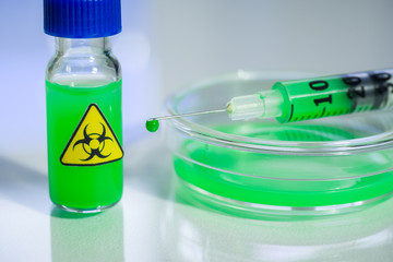 dangerous substance in a syringe, a vial and a petri dish on a table in a chemical laboratory