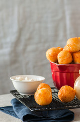 Small cottage cheese doughnuts (castgnole) served on a wire rack. White stone background.