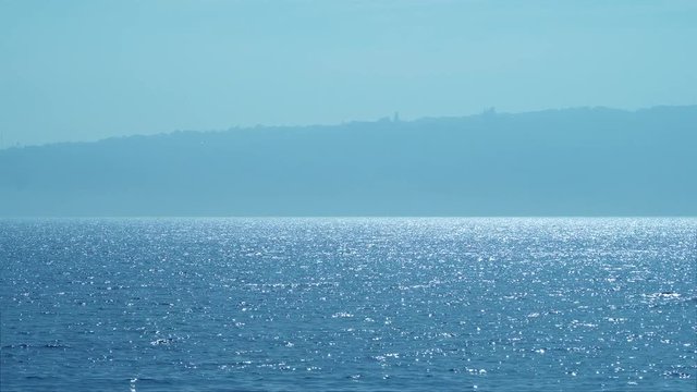 Sea idyll. The texture of the surface of the calm sea at dawn. A sunny path on the water. Bright background for a basic design