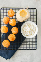Small cottage cheese doughnuts (castgnole) served on a wire rack. White stone background.