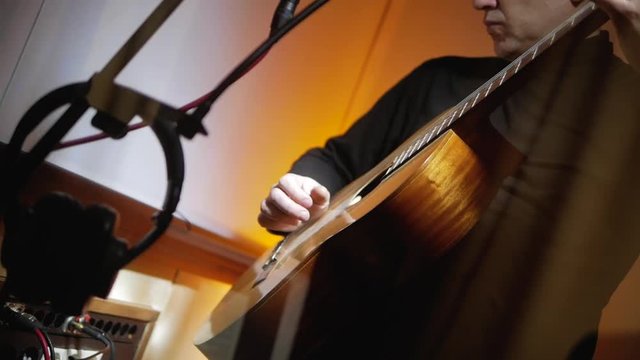Musician plays on acoustic guitar classic songs at record studio