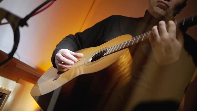 Middle age man plays music by acoustic guitar at sound recording studio close-up