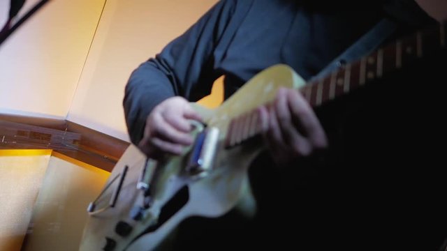 Guitarist plays rockabilly music by electric vintage guitar at music studio close-up 