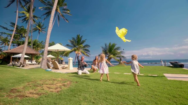 Happy caucasian family flying kite outdoors on green lawn