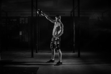 Fototapeta na wymiar Muscular male athlete pulls weight in the gym black and white filter