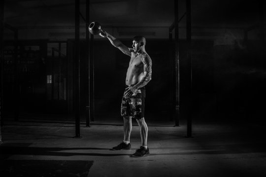 Muscular male athlete pulls weight in the gym black and white filter